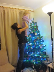 Hannah helping Kaylah put the star on top of the Christmas tree.